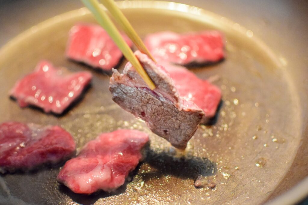 フライパンで肉を焼いている場面