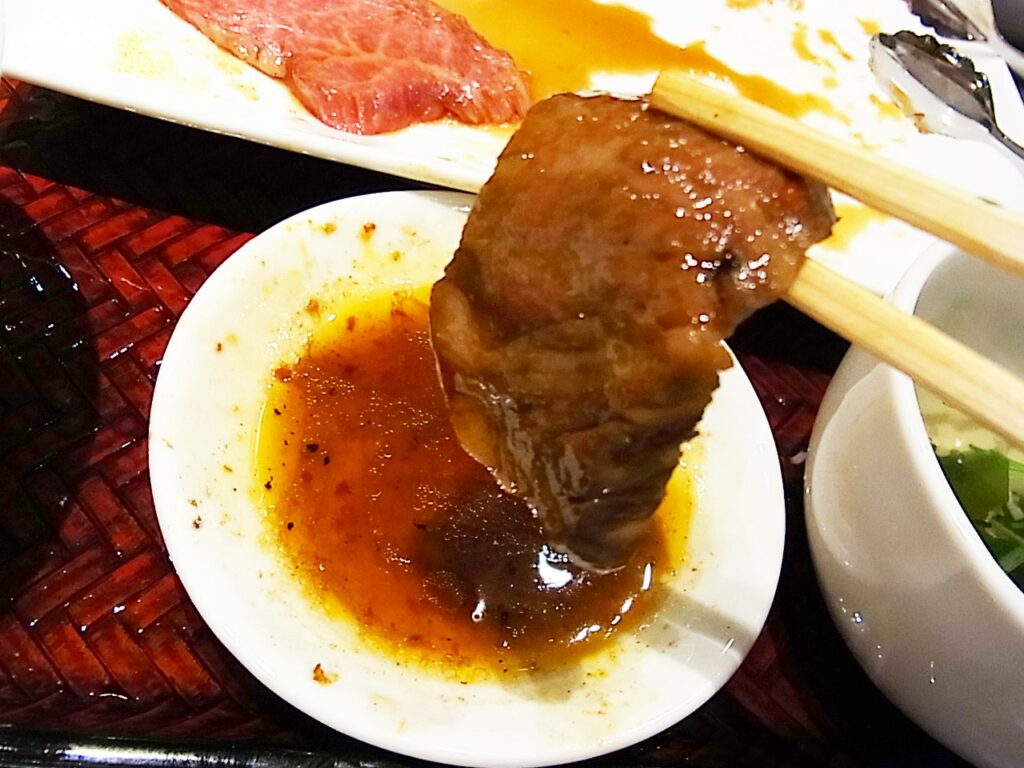 肉をタレに付けている画像